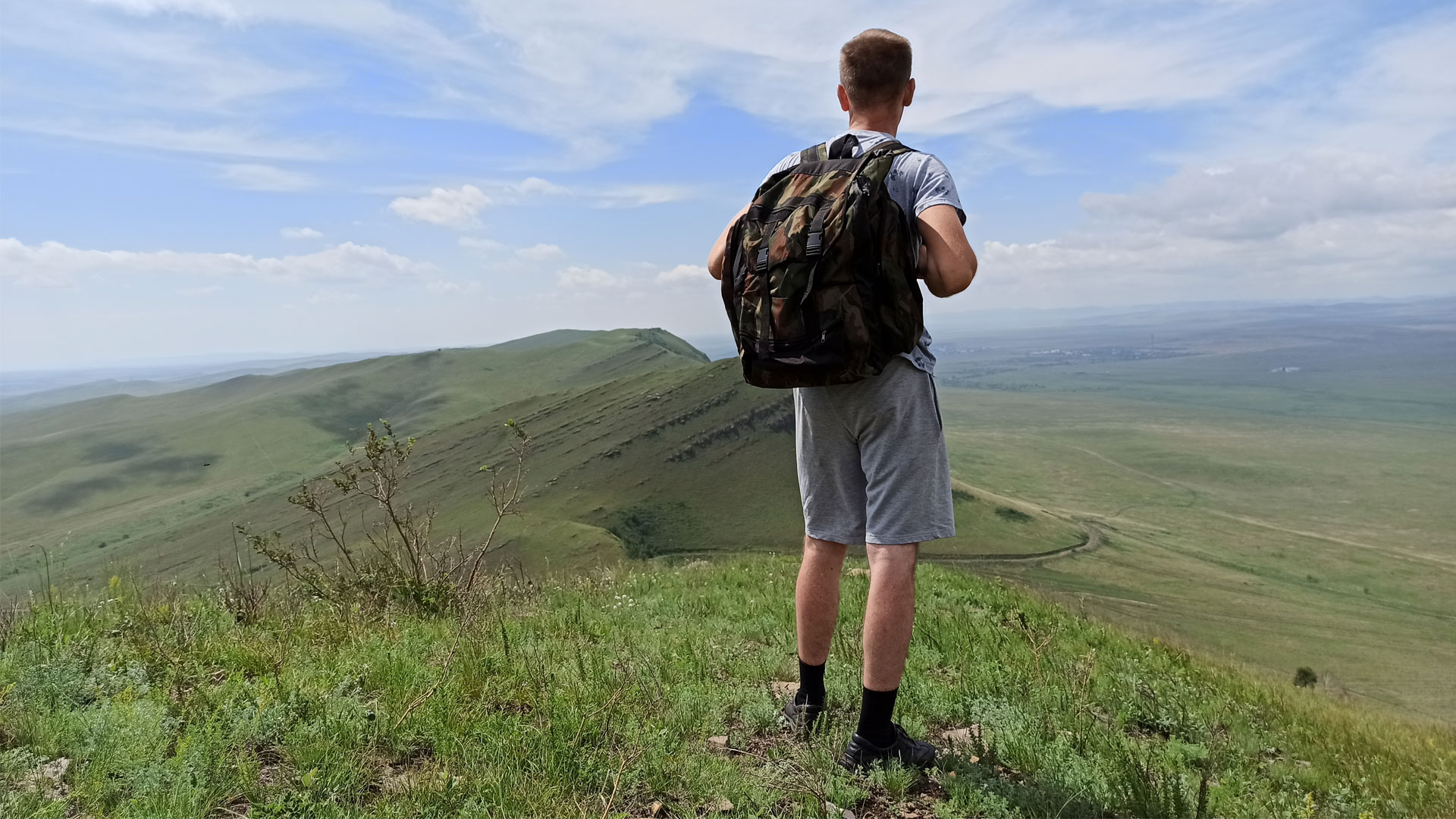 Вид на запад с горы Куня, человек с рюкзаком стоит спиной.